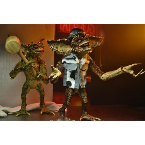 Neca presenta este set de 2 figuras de Gremlins en el éstos asaltan un salón de tatuajes. Esta escena se basa en la divertidísima secuela de Warner Bros, "Gremlins 2: La nueva generación". Cada figura mide unos 18 cms e incluye manos intercambiables, una máquina para hacer tatuajes, un mazo, unas gafas de sol, una fusta, una toalla de tela y un chaleco tejano.