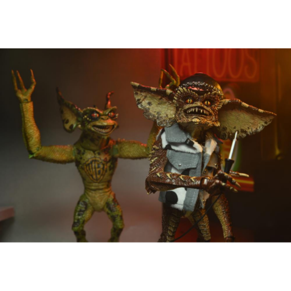 Neca presenta este set de 2 figuras de Gremlins en el éstos asaltan un salón de tatuajes. Esta escena se basa en la divertidísima secuela de Warner Bros, "Gremlins 2: La nueva generación". Cada figura mide unos 18 cms e incluye manos intercambiables, una máquina para hacer tatuajes, un mazo, unas gafas de sol, una fusta, una toalla de tela y un chaleco tejano.